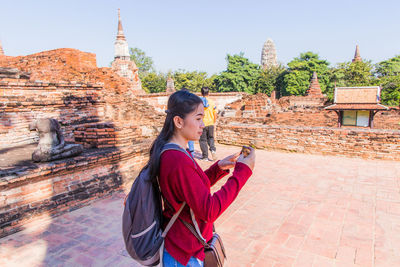 Side view of young woman against temple outside building