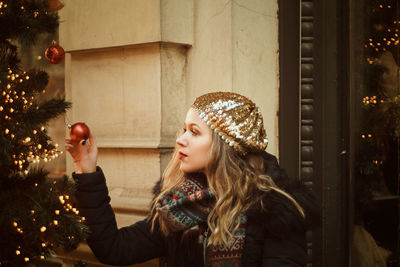 Portrait of young woman looking at christmas tree