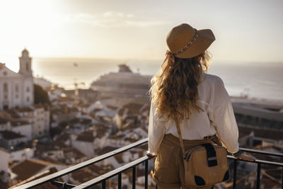 Rear view of woman looking at cityscape against sky