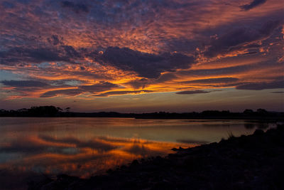 Scenic view of dramatic sky over lake during sunset