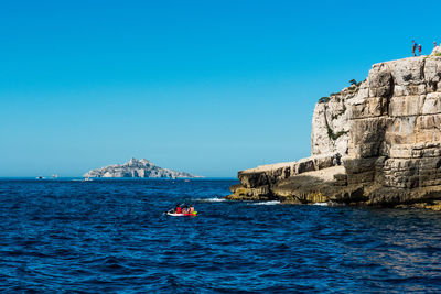 People on boat at sea against clear blue sky