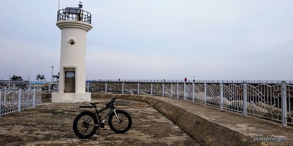 Bicycle by sea against sky