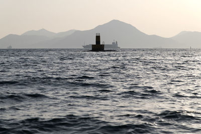 Silhouette boat sailing in sea against clear sky