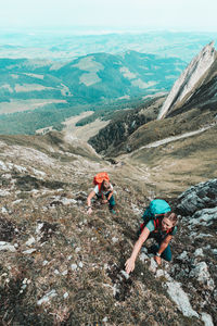 Front shot of women ascending steep cliff in swiss alps