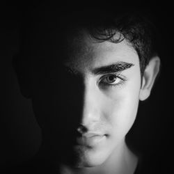 Close-up portrait of young man against black background