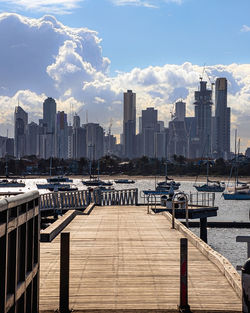 Boats moored at harbor by buildings against sky in city