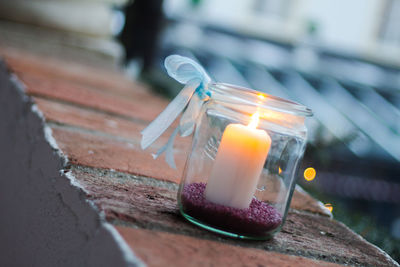 Close-up of candle in jar on retaining wall