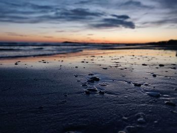 Surface level of beach against sky during sunset