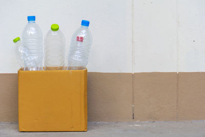 Close-up of bottle in glass on table against wall