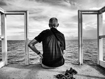 Rear view of man looking at sea against sky