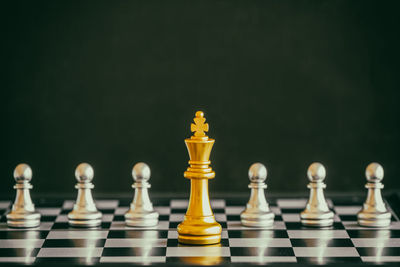 Close-up of chess pieces on board against green background