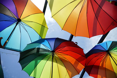 Low angle view of multi colored umbrellas hanging against sky