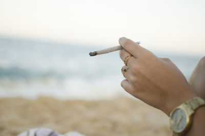 Midsection of man smoking cigarette against sky