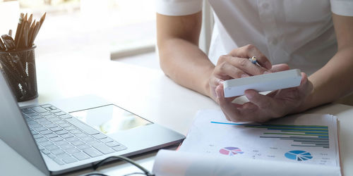 Midsection of man using laptop on table