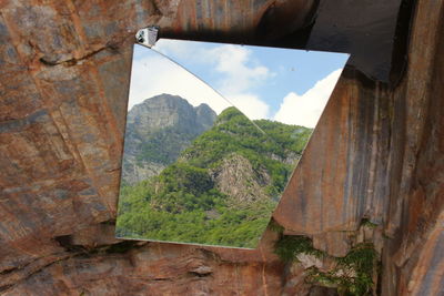 Reflection of tree mountains on mirror mounted at rock