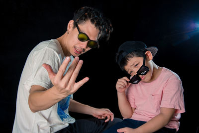 Portrait of father and son against black background