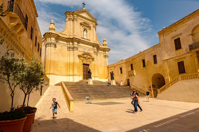 People at historic building against sky