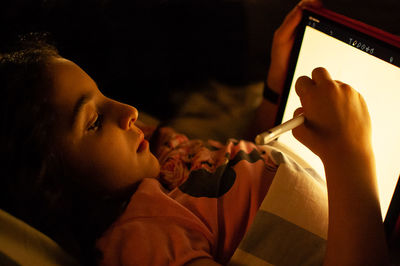 Side view portrait of girl holding mobile phone at home