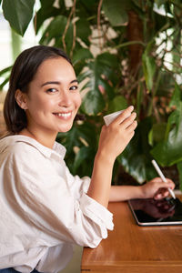 Portrait of young woman sitting on table