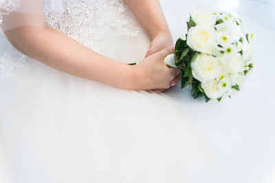 Midsection of bride holding bouquet