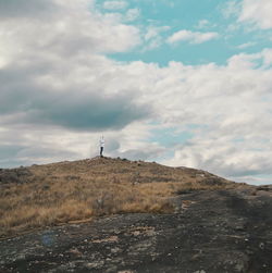 Man standing on mountain against cloudy sky