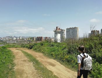 Rear view of man walking on landscape against sky