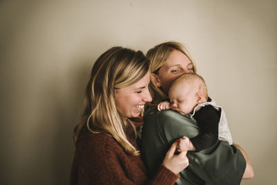 Smiling mothers hugging sleeping newborn baby