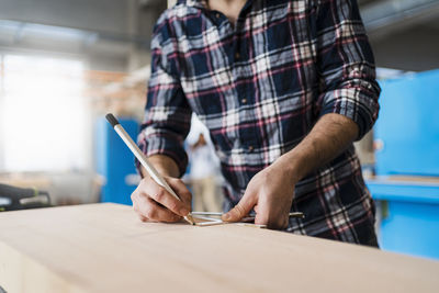 Manual worker measuring wood while working at industry