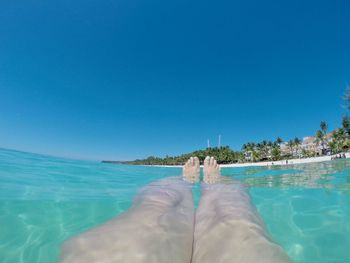 Low section of person in swimming pool against sea