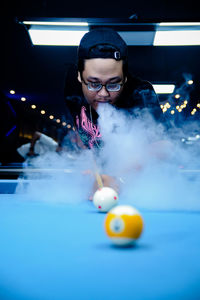 Portrait of young woman playing pool