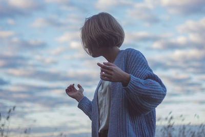 Rear view of boy standing against sky