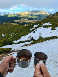 Midsection of person holding ice cream against mountains