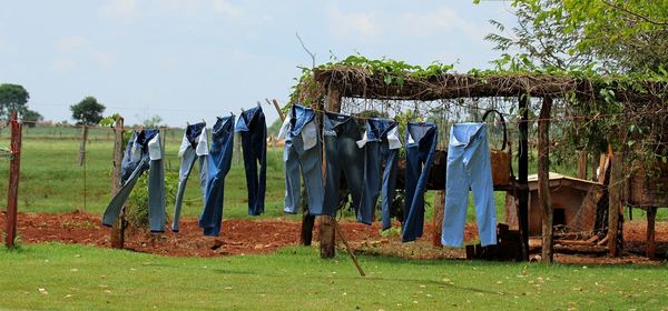 Clothes drying on clothesline on field against sky