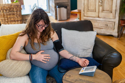 Woman using mobile phone while sitting on sofa at home