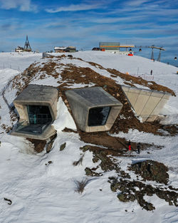 Snow covered houses by building against sky