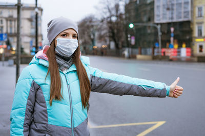 Portrait of young woman standing on road in city