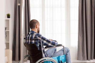 Young man sitting by window at home