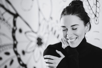 Portrait of smiling young woman standing against graffiti