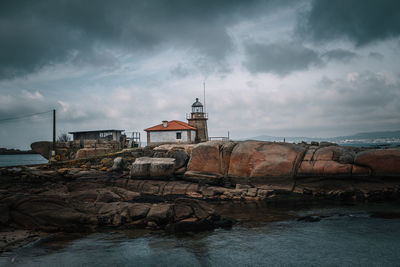 Lighthouse on beach against buildings