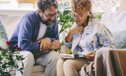Smiling man with woman reading book at home