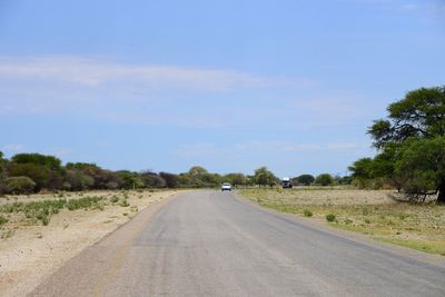 Road amidst trees against blue sky