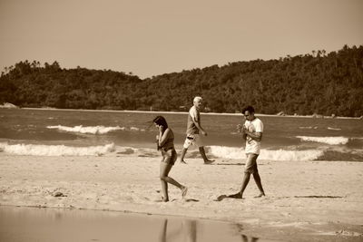 People playing on beach against sky