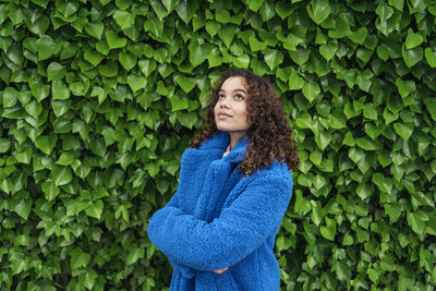 Beautiful young woman standing by plants