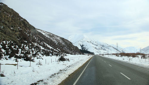 Road by snowcapped mountain against sky