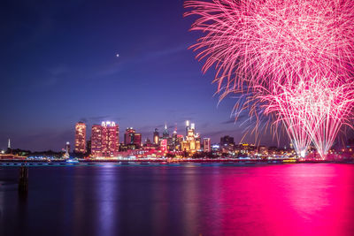 Firework display over illuminated buildings in city at night