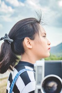 Portrait of woman holding a camera   against sky