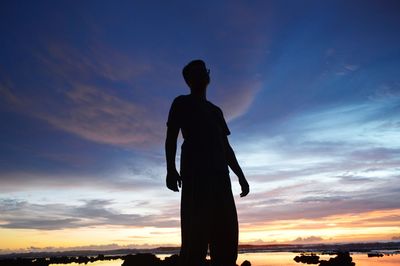 Silhouette man looking at sunset sky