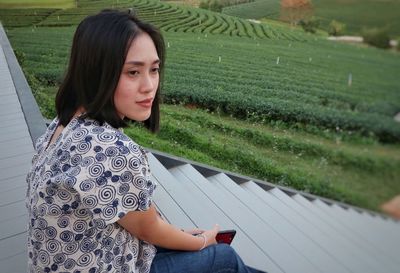 Young woman sitting by field on steps