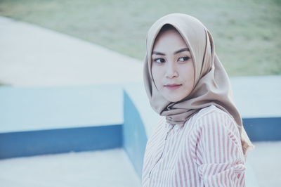 Portrait of young woman standing against water