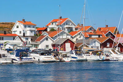 Sailboats moored on sea by buildings against clear sky